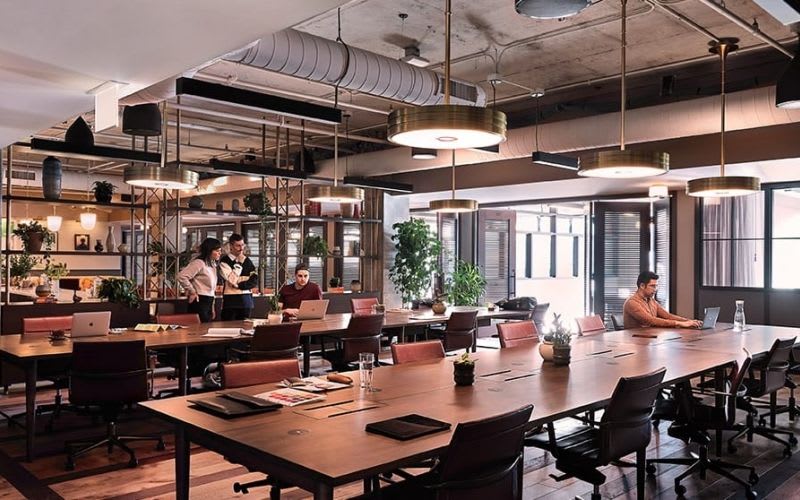 Co-working space with two long tables and a couple people working.