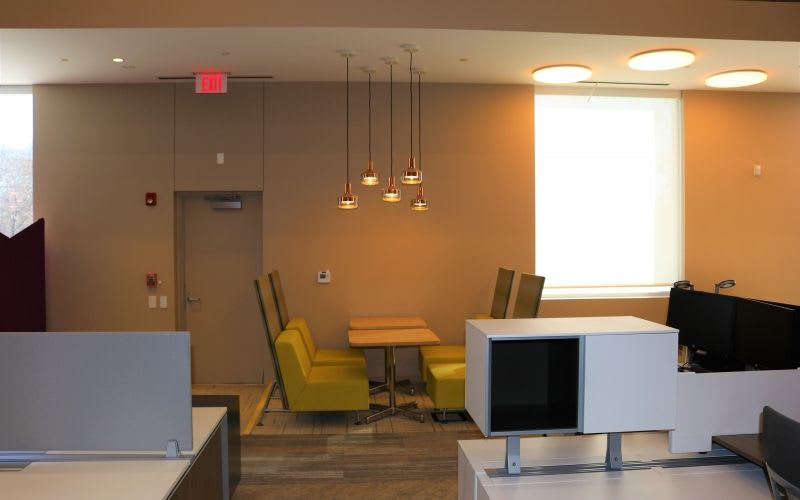 Hallway of Foward Space showcasing some warm lighting, light pendants and a couple chairs and tables.