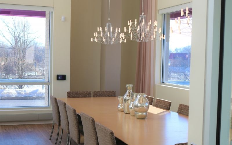 A long table with chairs, a centerpiece and some bright chandeliers.