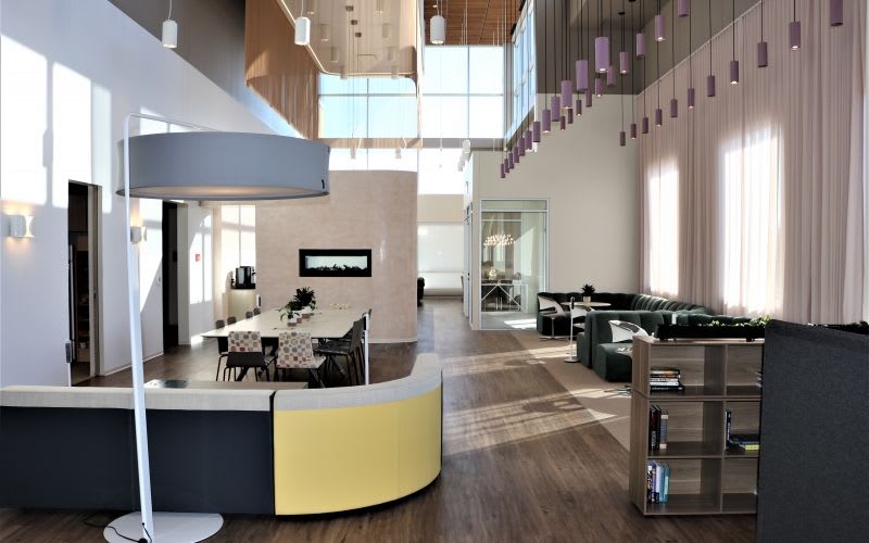 Office working space with tables, light pendant fixtures and a large, modern floor lamp.