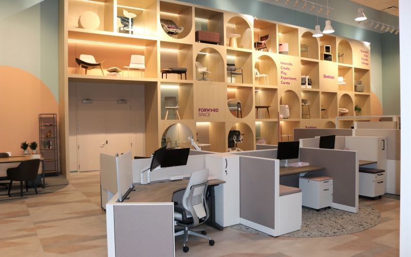 Co-working space at Forward Space with a tall wall unit that showcases brightly lit chairs inside it.