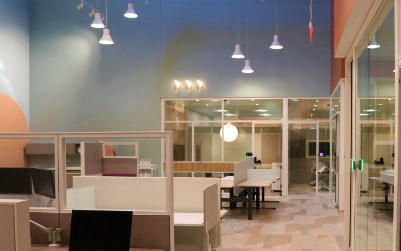 Large working space with a couple cubicles and meeting rooms across from them.