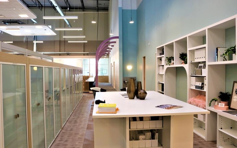 View of the hallway which includes a large table, bookshelf and hanging lights.