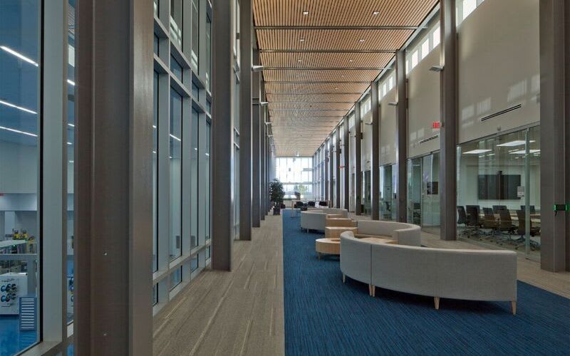 Long hallway with couches and seating in the center and meeting rooms across them.