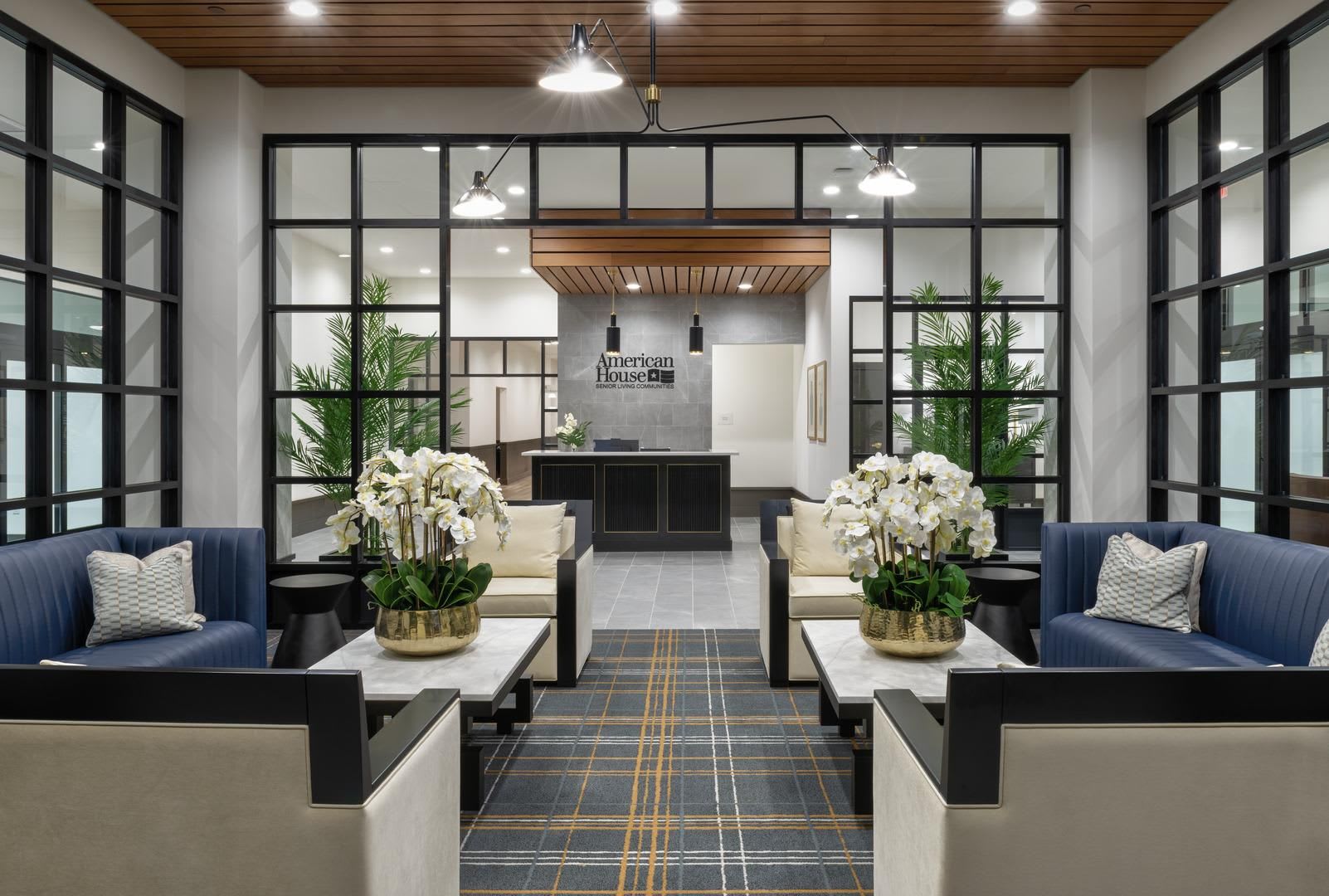 The lobby lounge at American House Oak Park Senior Living with comfortable couches, flowers and bright lighting.