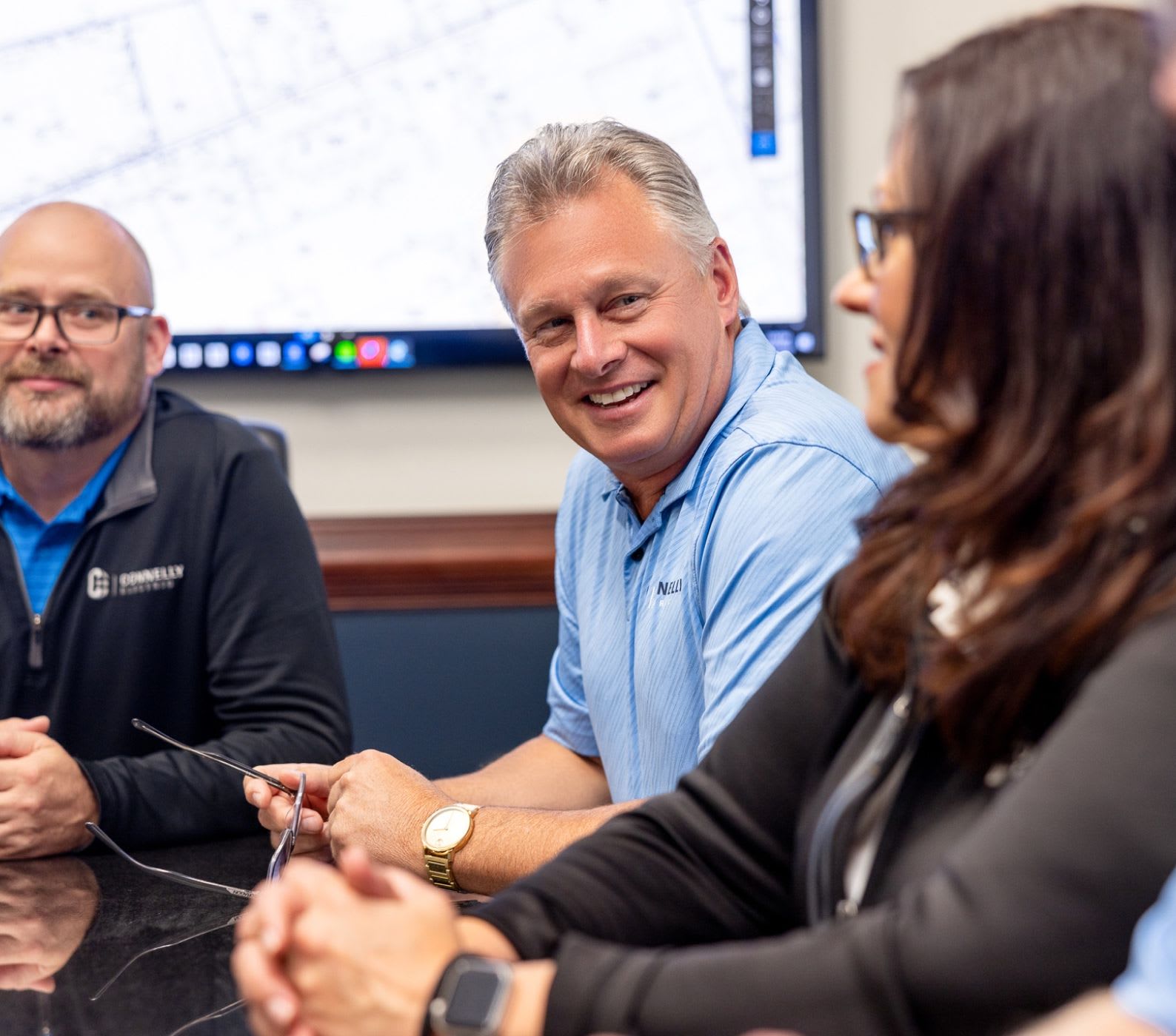 Connelly Electric employees sitting in a board room during a meeting and smiling.