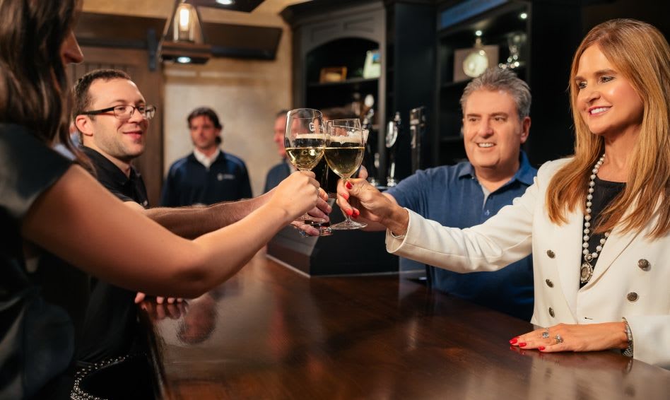 Four Connelly leaders with wine glasses cheering together and smiling.