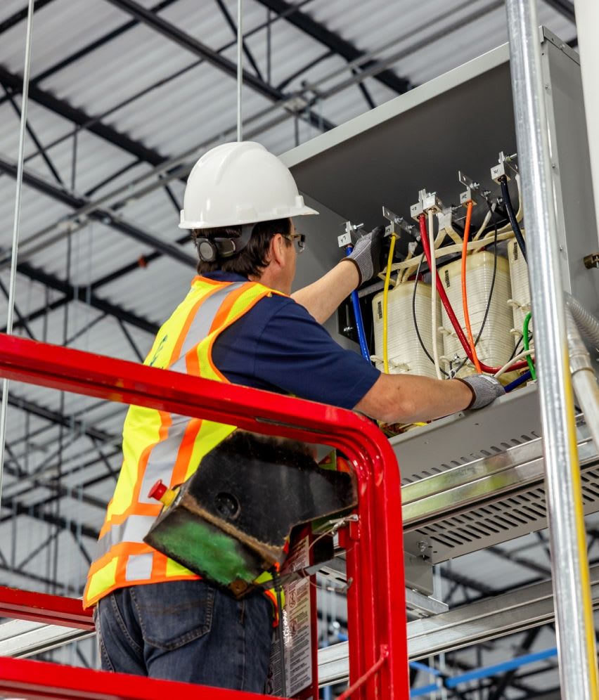 Connelly Electric service technician providing general electric maintenance in a hard hat and safety vest.
