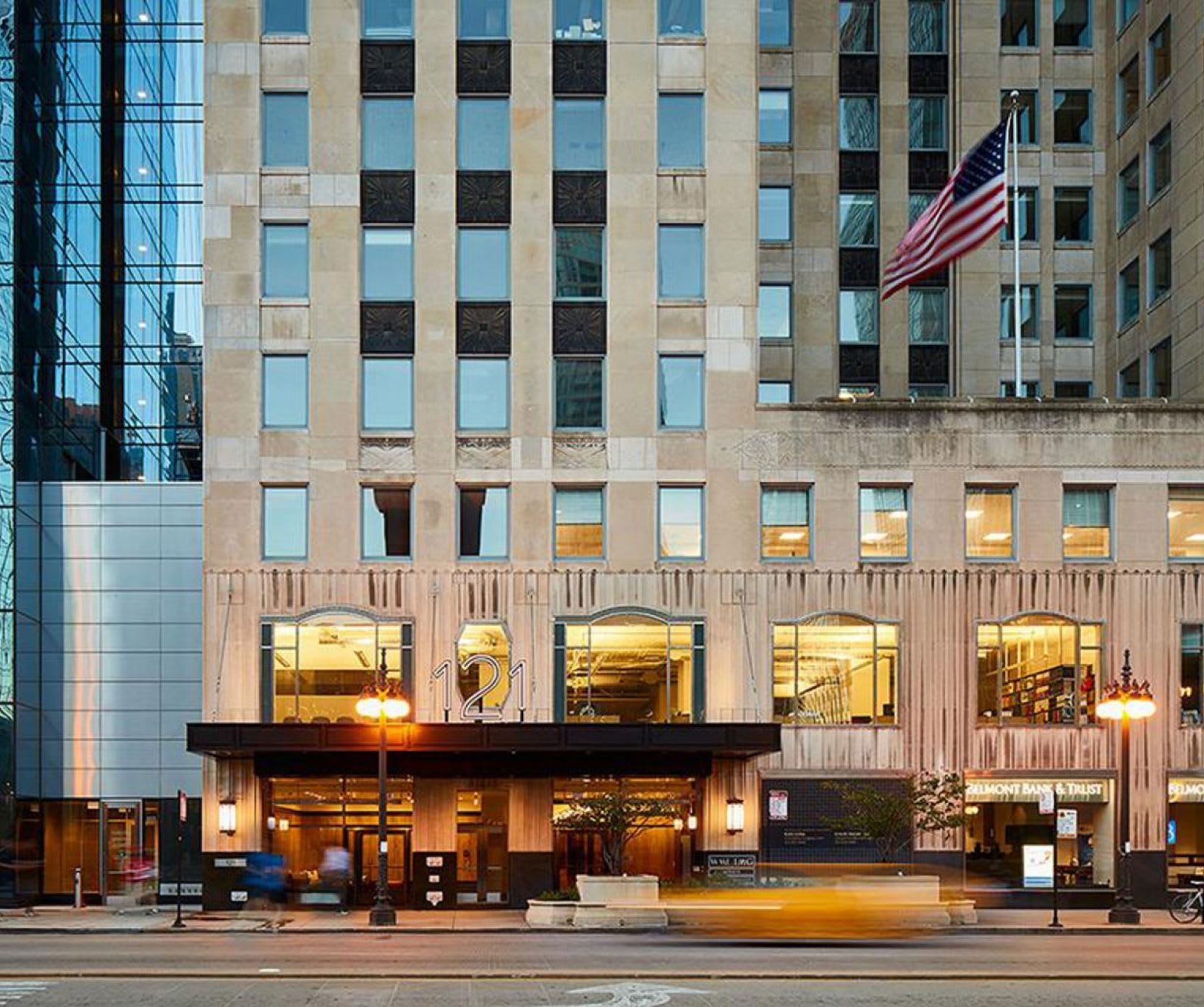 The outside view of a high-rise building showing the front entrance illuminated and the numbers "121".