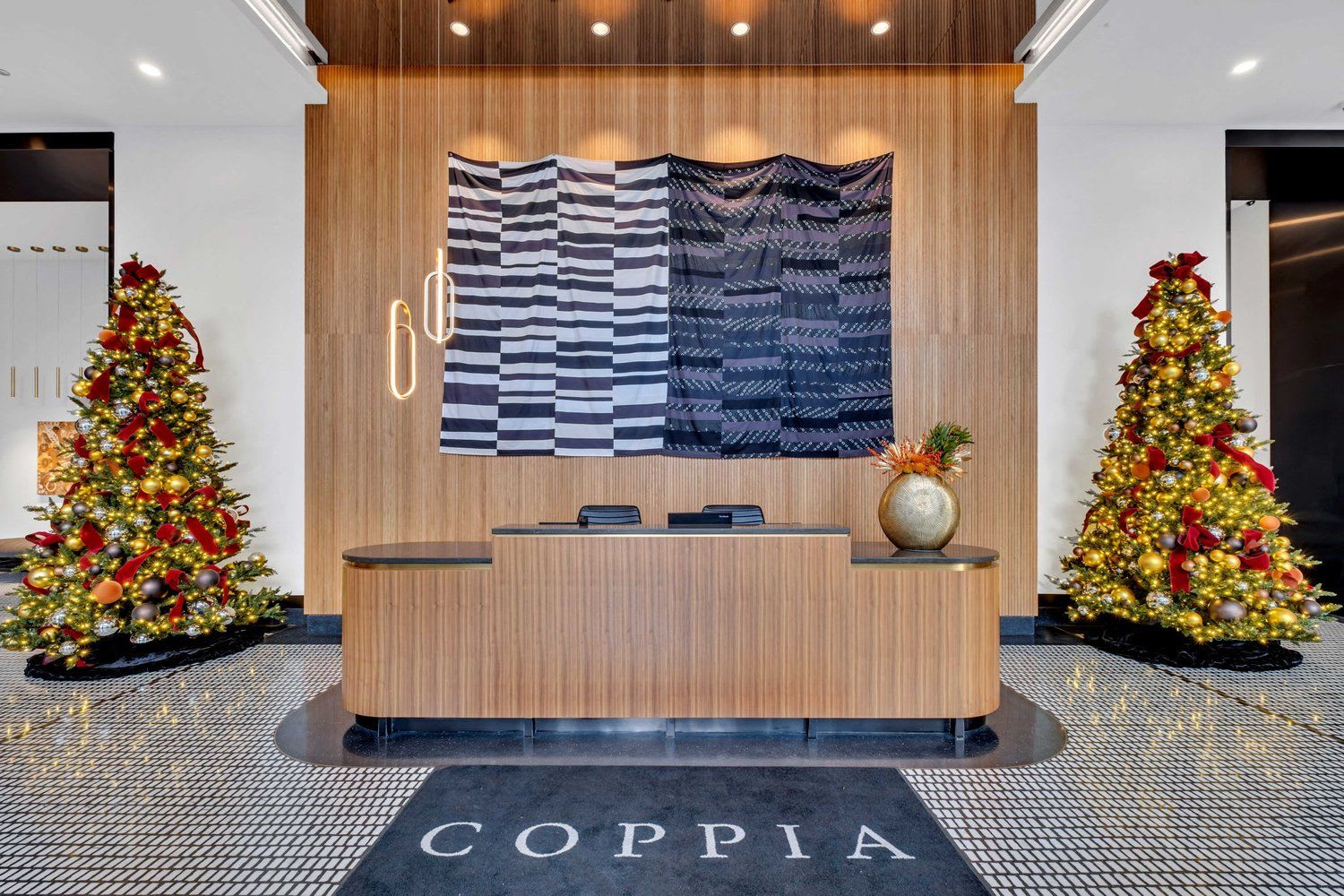 Lobby entrance with wood paneling, ceiling lights and two Christmas trees on each side of the desk.