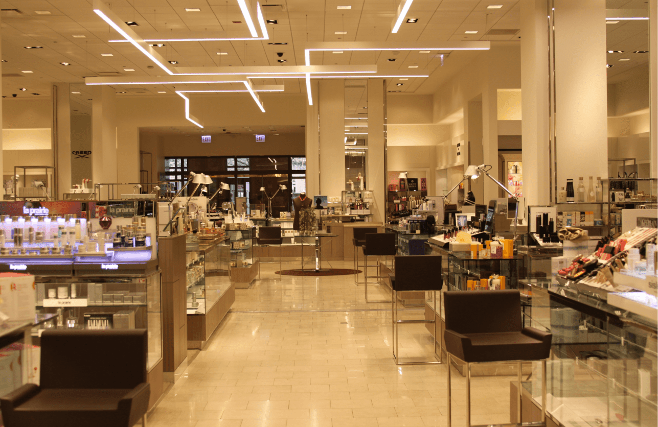The perfume and makeup section inside Neiman Marcus Chicago, illuminated by linear pendant lights.