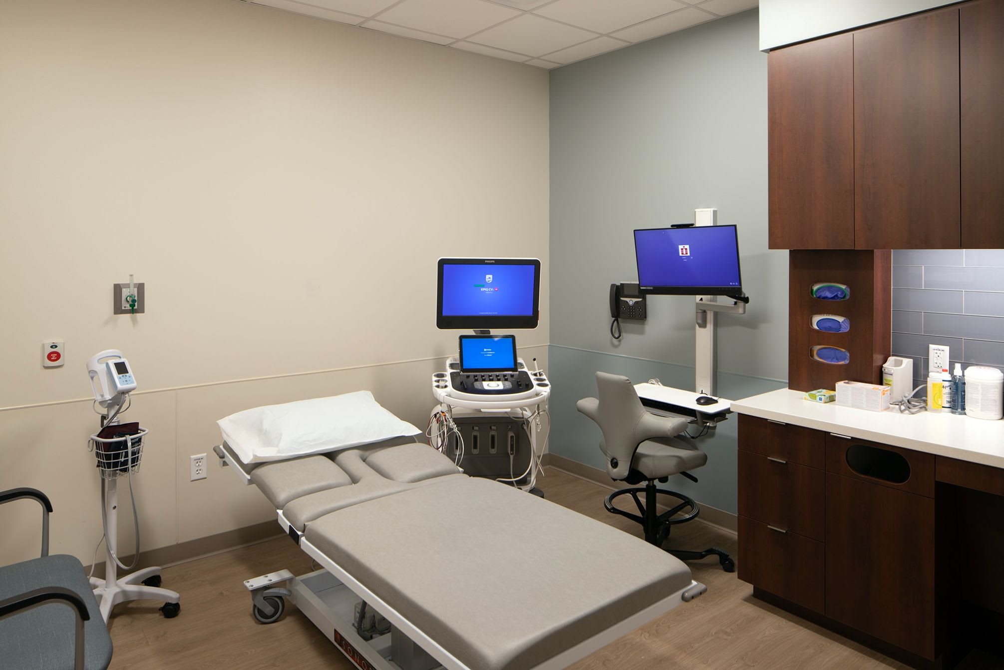 A patient room with an ambulatory bed and a couple computer screens.