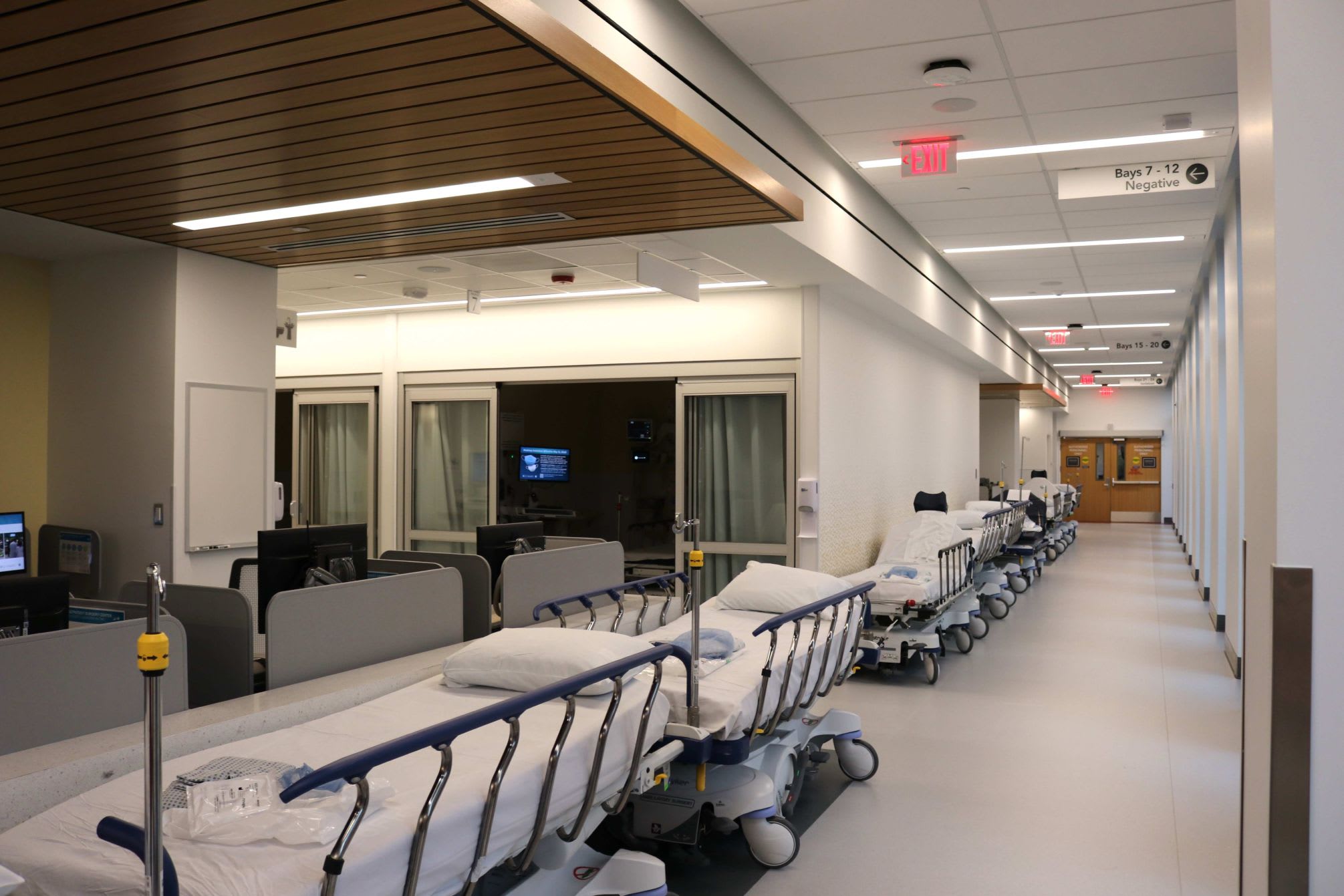 Long hallway of a medical building showing a couple ambulatory beds.
