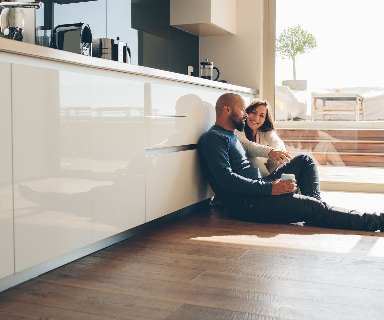 married couple sit on the floor of their kitchen together