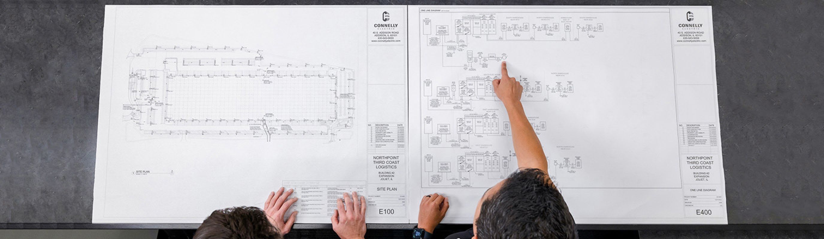 Two Connelly Electric Engineers reviewing blueprints.