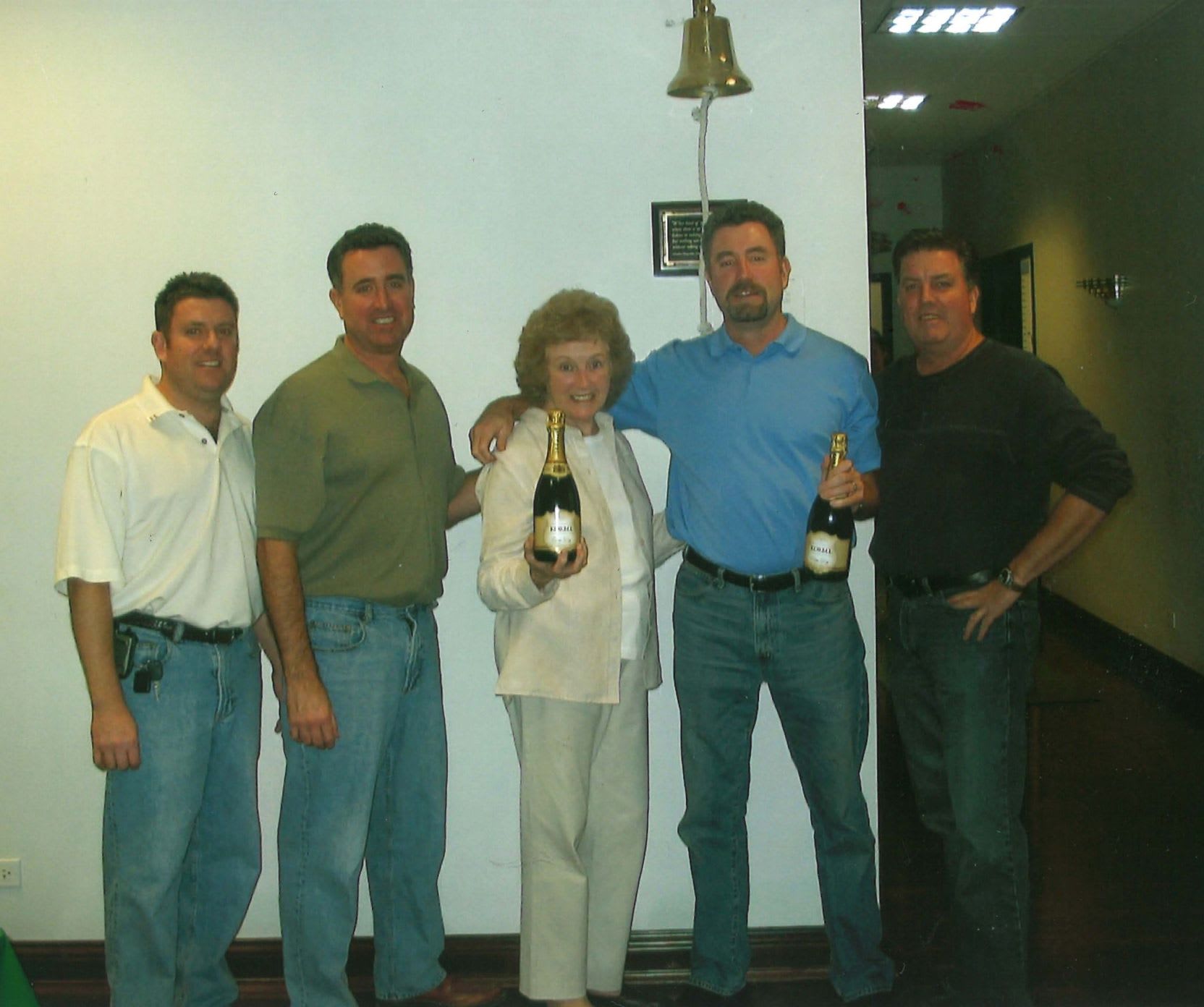 Five members of the Connelly family standing together, smiling and holding two bottles of champagne to celebrate Connelly's expansion.