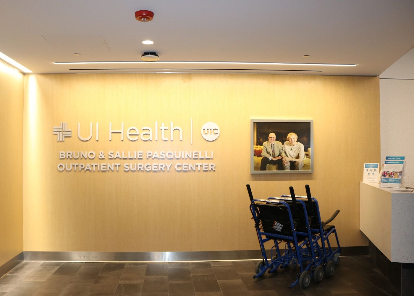 Wall with a UI Health logo, a photo of two people and writing underneath that says "Bruno & Sallie Pasquinelli Outpatient Surgery Center".