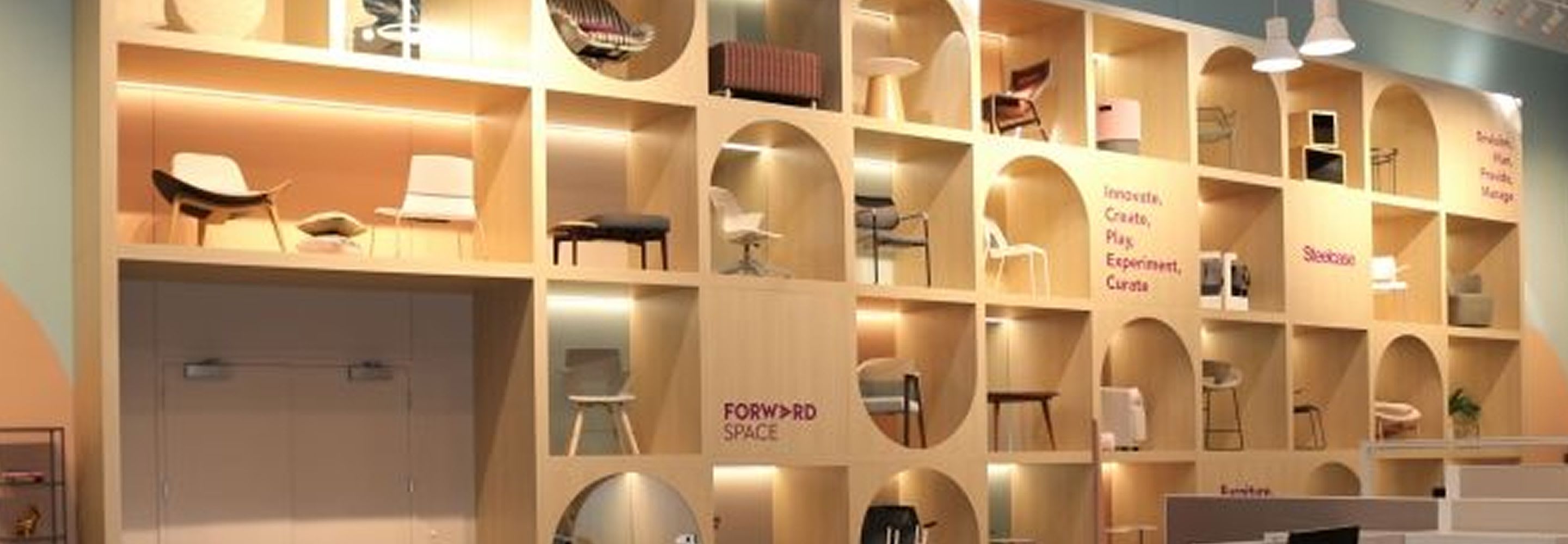 Co-working space at Forward Space with a tall wall unit that showcases brightly lit chairs inside it.