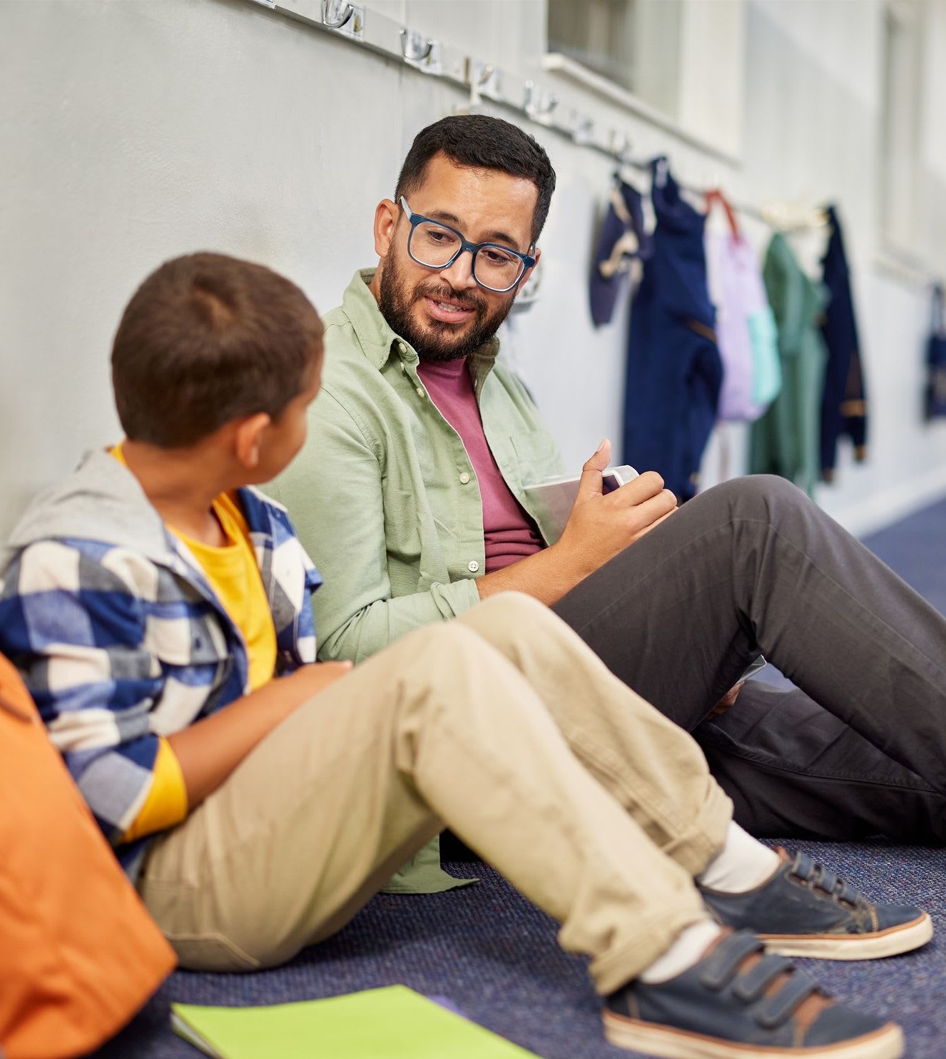 a teacher sitting on the floor with a 1st grader