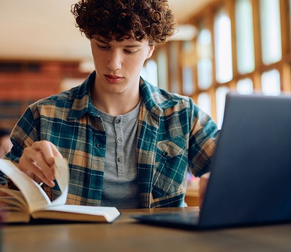 student flipping through a book in a library