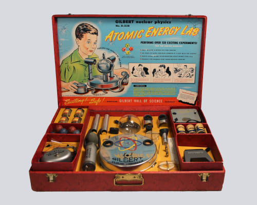 Toy science kit containing multiple pieces and showing the words "Atomic Energy Lab" on it.