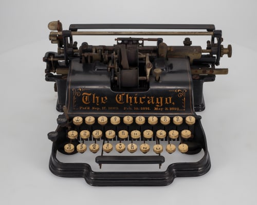 A black, metal historical typewriter with the words "The Chicago" on it.