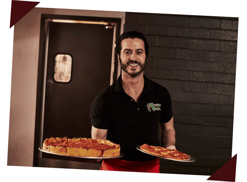 A Beggars Pizza server wearing a branded polo and a red apron holds a deep-dish pizza and pepperoni pizza, smiling
