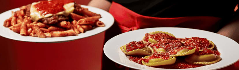 Close-up of a server holding 2 plates of pasta