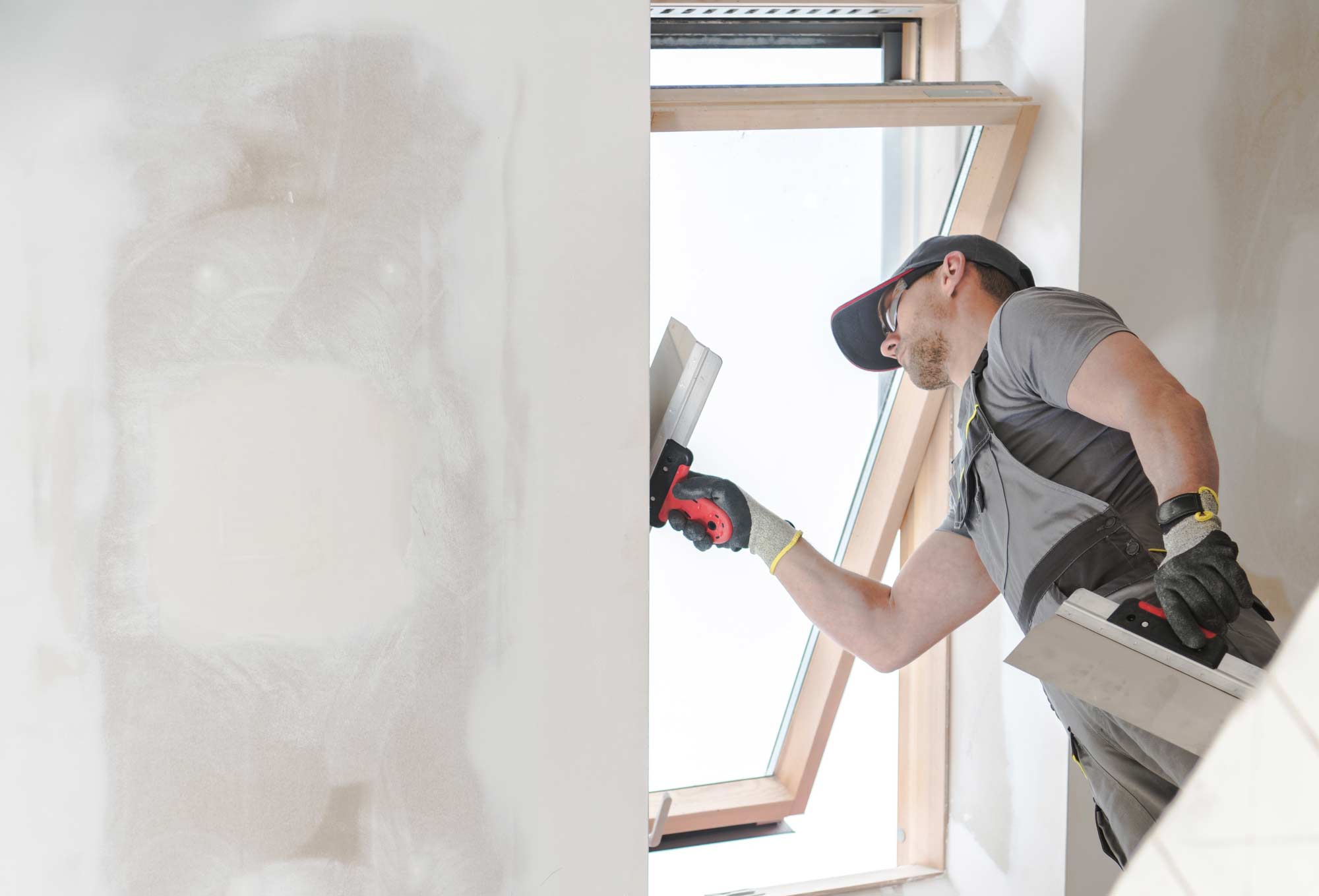 A construction worker finishing up a wall inside a new building