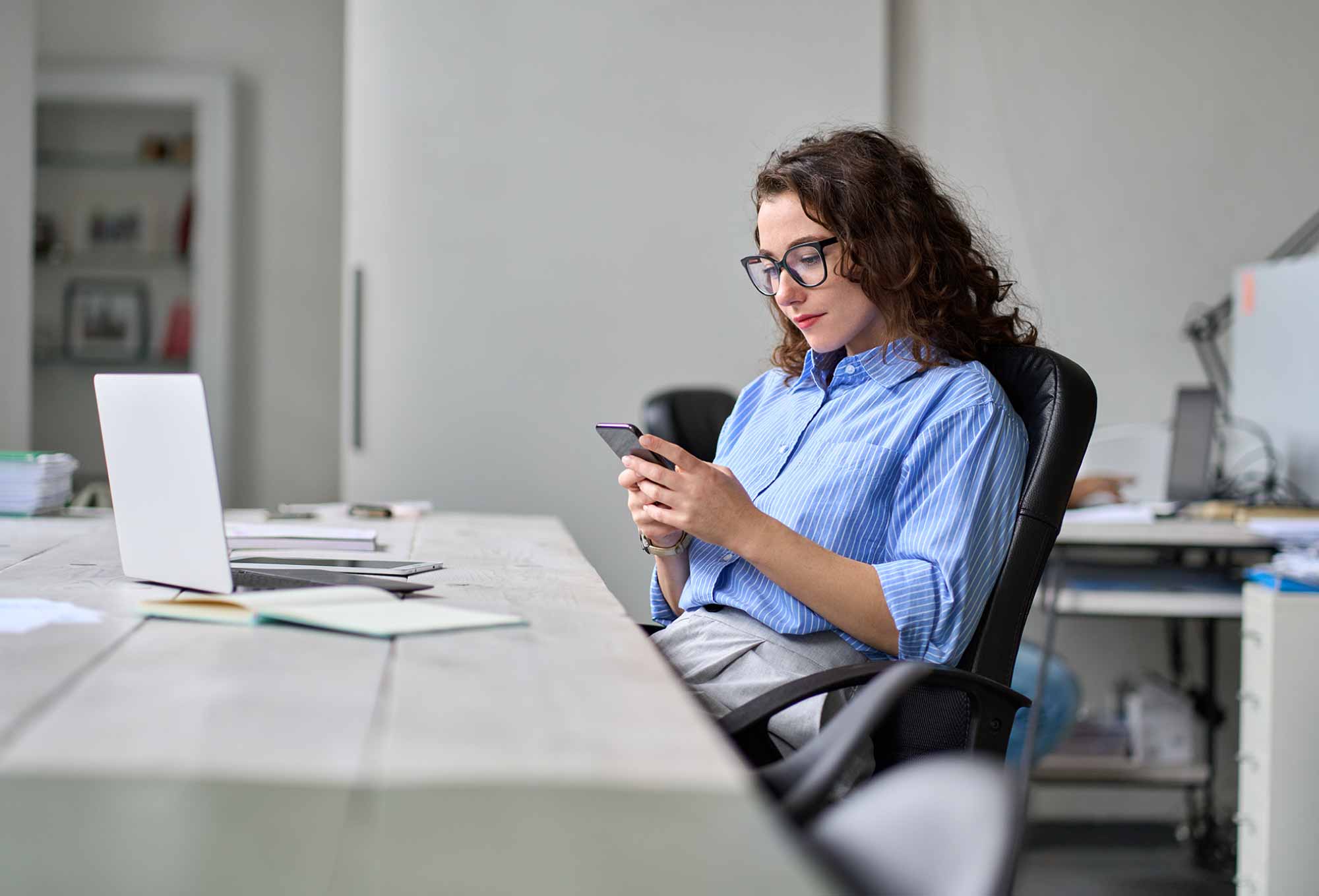 woman writing on iphone at desk