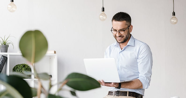 a man with glasses using his white laptop