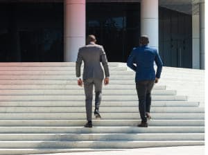 Two men wearing suits and walking up stairs 