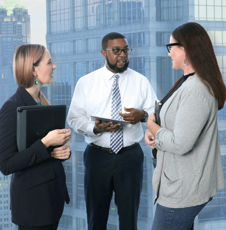 Three businesspeopl e talking in front of an office window | DOT Cybersecurity Services