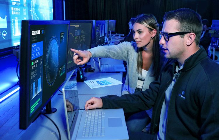 A man and a woman pointing at a computer on a desk | Cybersecurity Services
