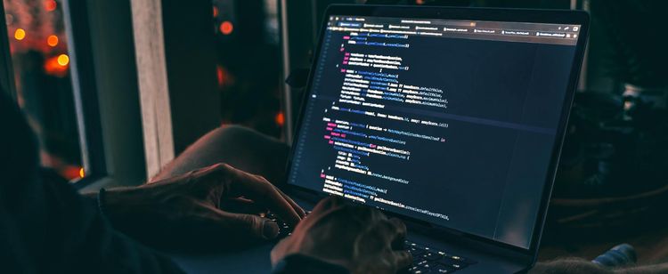 Man using a laptop in dimly lit room | Importance of Compliance in 2021