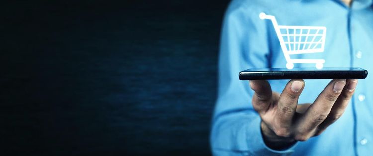 Man holding a tablet in his hand with an abstract shopping cart projected out of it | 7 Must-Have Security Measures for Ecommerce Websites