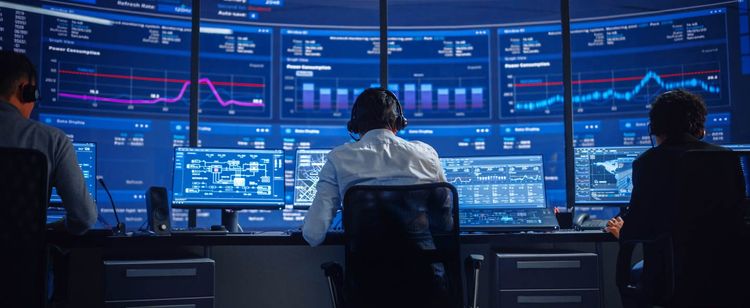 Developments Shaping the Future of Cybersecurity | Shot of man sitting at desk with his back turned to the camera, working at a computer with large screens