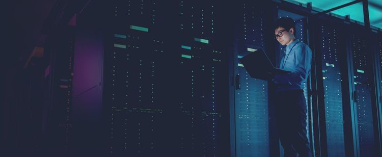 man typing on computer in server room