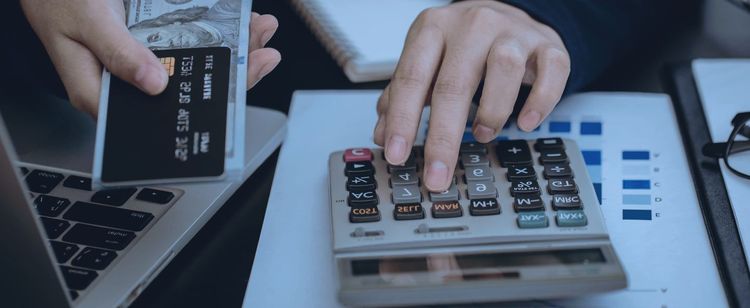 A person doing accounting on their calculator | How Much Do Companies Spend on Cybersecurity? | Minimize Your Losses