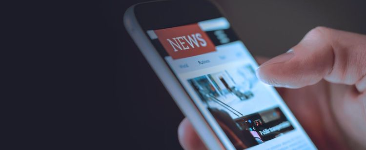 A cellphone with news articles showing on the screen | 5 Notable Cybersecurity Articles in 2022: Year in Review | DOT Security