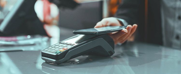 person paying with phone at point of sale (POS) system in business