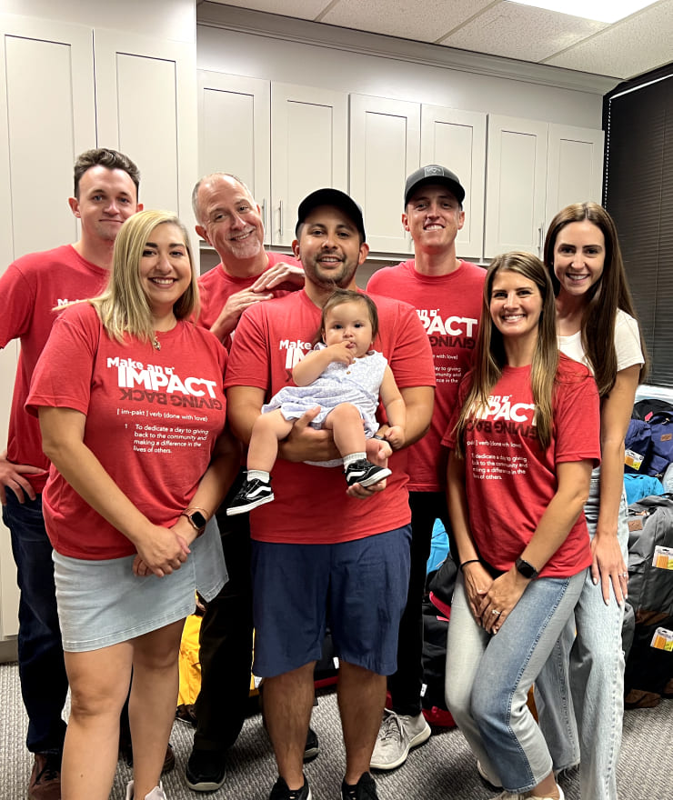 a group of people wearing red Impact shirts posing for a photo