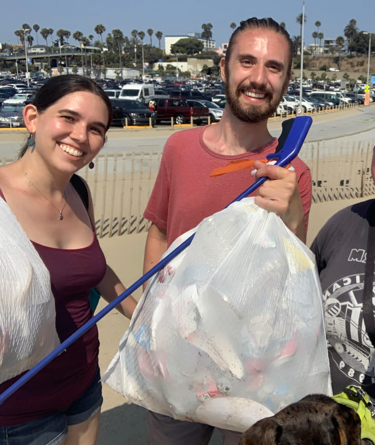 four people cleaning up trash on a beach in California
