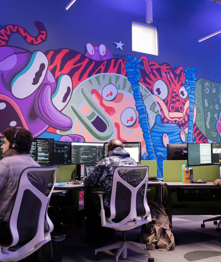 people working on computers with colorful mural in the background