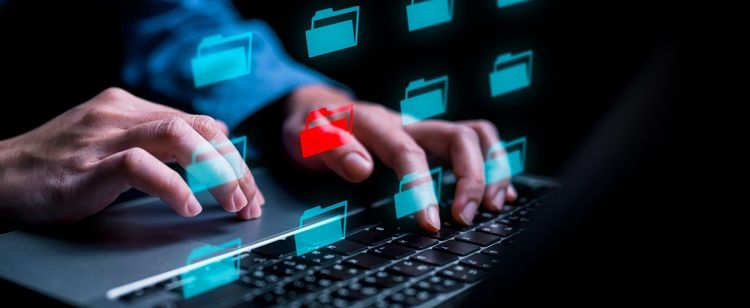 Translucent laptop screen with file folders illuminated and person typing on keyboard
