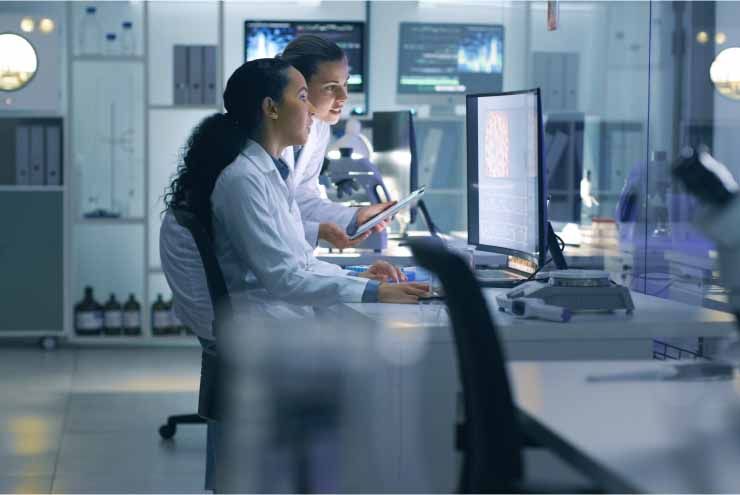 Two people in labcoats at computer in office setting