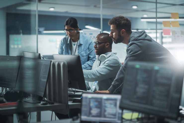 Three men having discussion over shared computer monitor