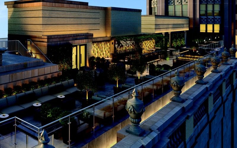 The outside rooftop terrace of the London House with multiple lights illuminating it at night.