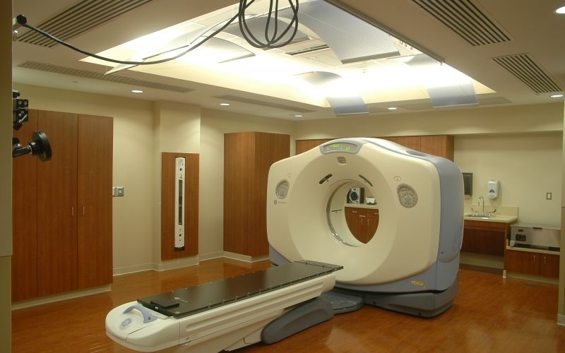 An MRI suite with MRI equipment and wood floors and containers.