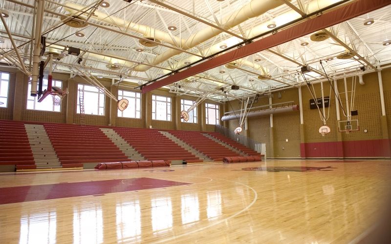 Basketball court with wood floors and natural light coming in through the windows.